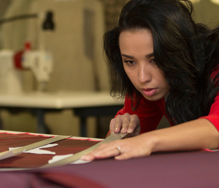 A student measuring and cutting fabric
